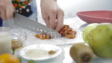 双手用大刀在砧板上切碎干燥的杏。 烹饪健康食品
